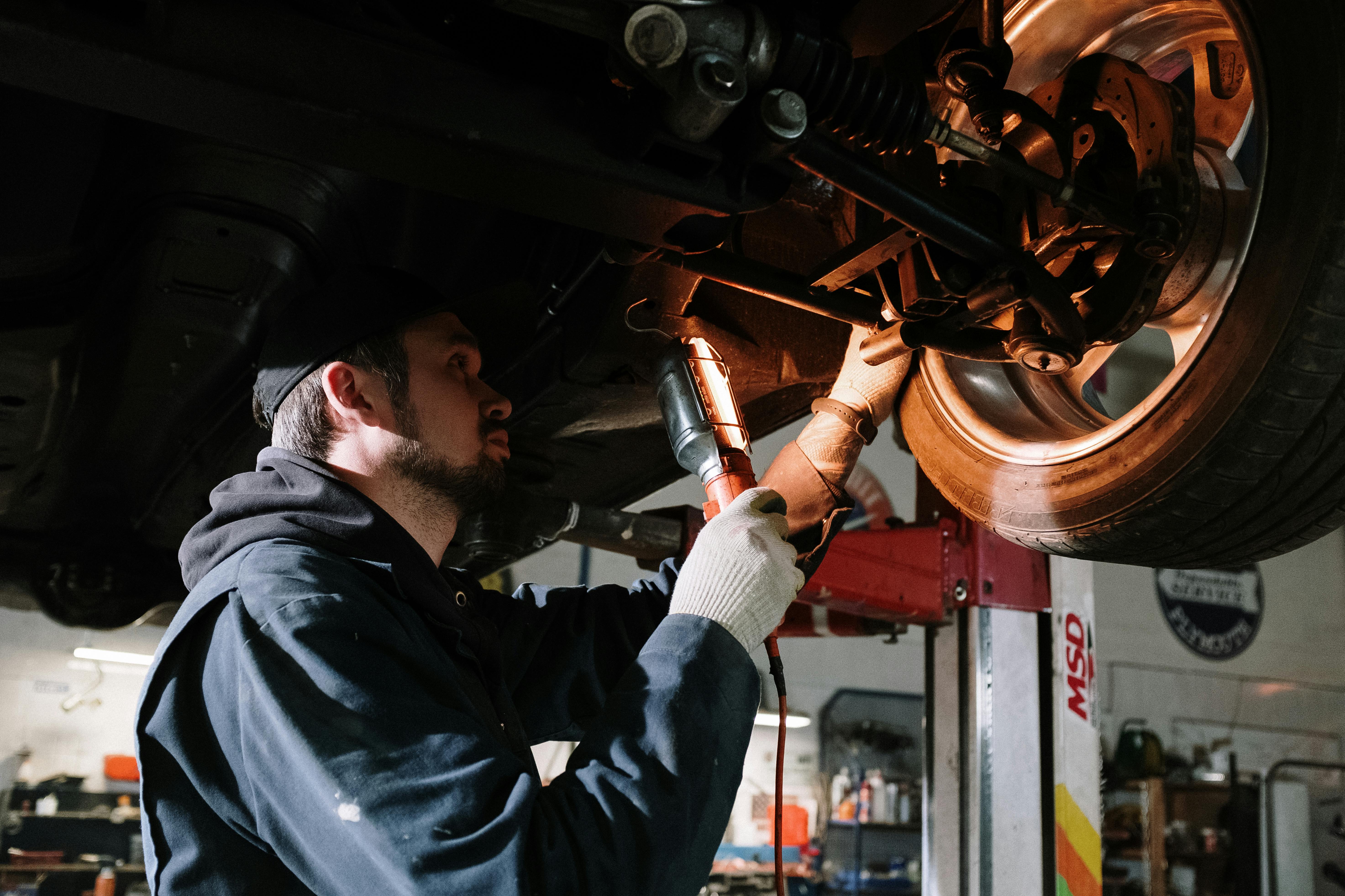 Mechanic inspecting vehicle suspension and wheel assembly